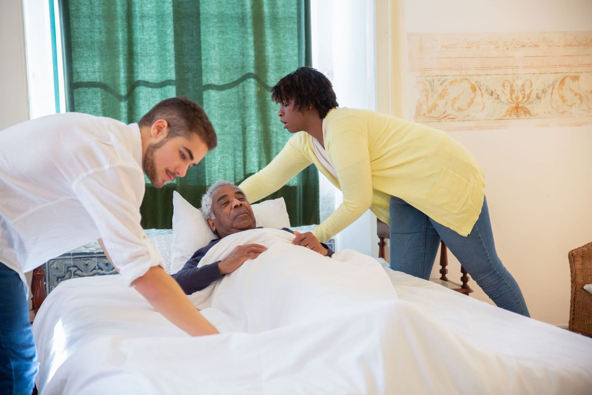Two caregivers assisting one person together at the bedside